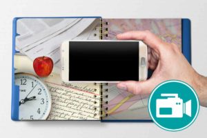 Ein SMartphone ist zu sehen. Im Hintergrund einUhr, eine Landkarte und Zeitungen.