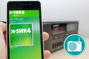 Im Vordergrund ist ein Smartphone, im Hintergrund steht ein Radio.