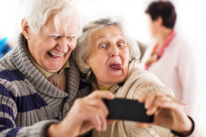 Cheerful senior couple making faces and having fun while taking a selfie with smart phone.