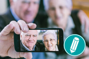 Zwei ältere Menschen machen mit dem Smartphone ein Selfie, fotografieren sich also selbst.