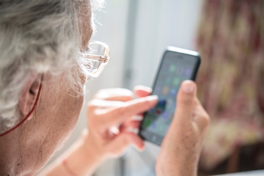 Eine ältere Frau tippt auf ihr Smartphone.