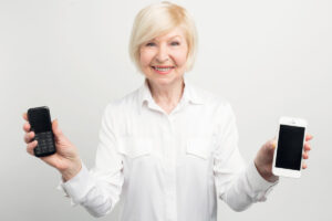 Ältere Frau hält zwei Smartphones in der linken und rechten Hand.