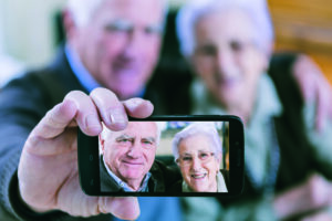Senior couple showing self portrait photo on smartphone