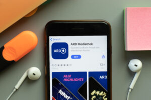 Smartphone mit Kopfhörern. Die App "ARD Audiothek" ist geöffnet.