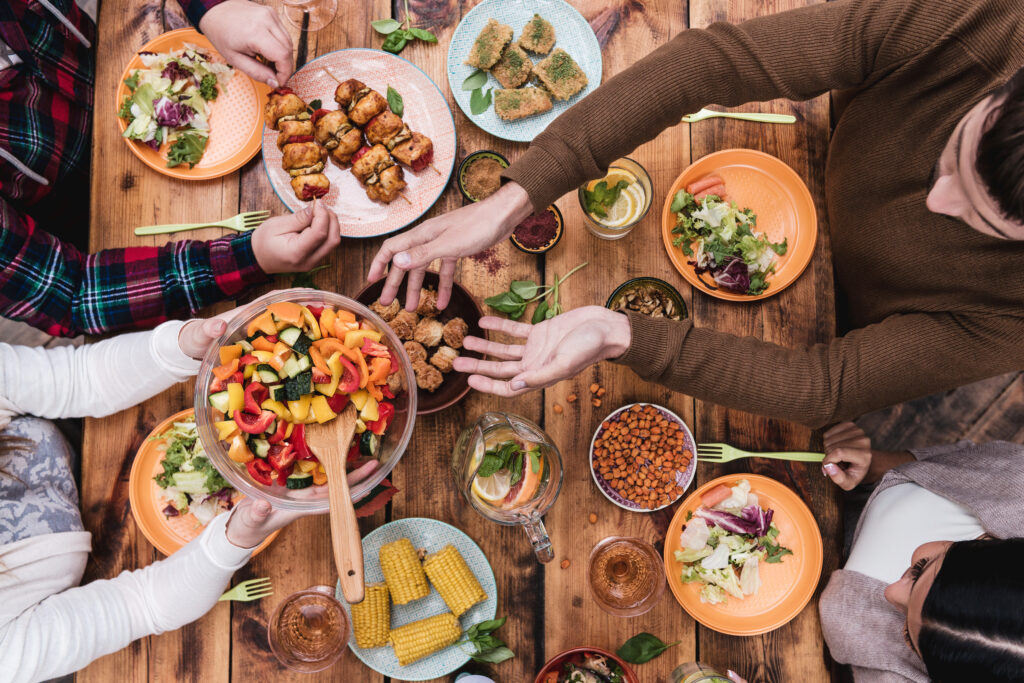 Menschen reichen sich Essen über den Tisch