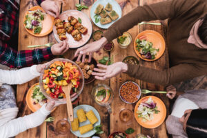 Menschen reichen sich Essen über den Tisch