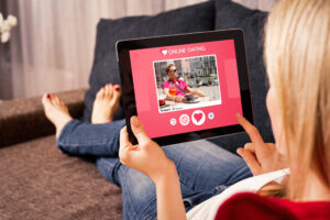 Frau hält Tablet in der Hand, auf dem eine Online-Dating-Plattform zu sehen ist