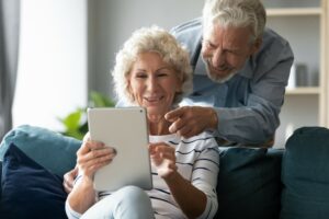 Zwei ältere Menschen schauen gemeinsam auf einen Tablet-Computer
