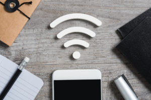 Top view of smartphone on desk searches a free wifi connection available. High angle view of smart phone with white wi-fi sign on top. Internet technology and networking concept.