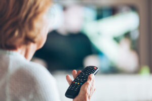 Senior woman with remote control watching television